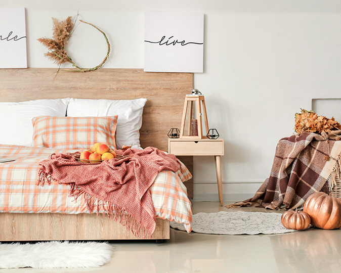 Stylish interior of room with big comfortable bed and autumn décor.