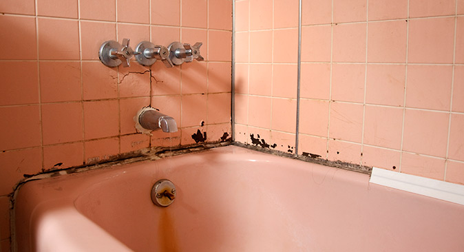 An old dirty bathtub has missing caulk and needs caulk for proper sealing.