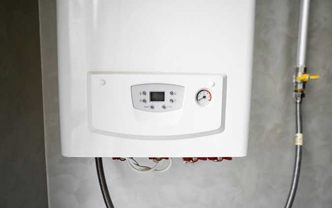 A modern tankless water heater mounted inside on a grey wall.